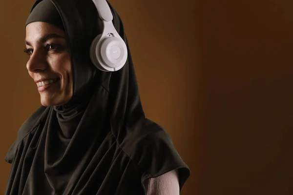 Молода Мусульманка Хіджабі Слухає Музику Навушниками Ізольовані Коричневому Фоні — стокове фото