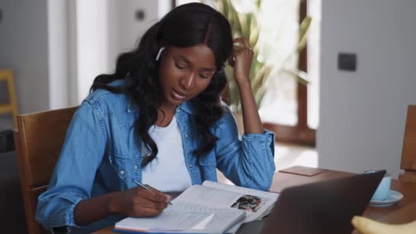 全神贯注的非洲女人用耳机说话 在家写些什么 — 图库视频影像