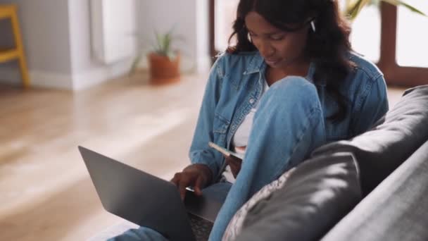 Pensive Afrikaanse Vrouw Dragen Oordopjes Invoeren Van Iets Van Telefoon — Stockvideo