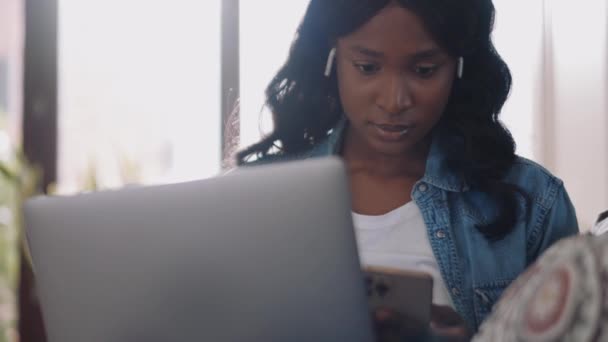 Mujer Africana Concentrada Usando Auriculares Mensajes Texto Teléfono Casa — Vídeos de Stock