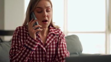 Yakışıklı sarışın kadın kahvaltı yapıyor ve evde telefonla konuşuyor.