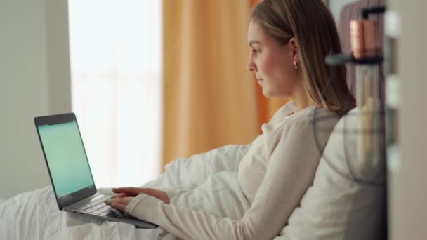 快乐的金发女人在家里的床上用笔记本电脑工作 — 图库视频影像