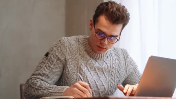 Sorrindo Homem Vestindo Óculos Escrevendo Algo Laptop Para Notepad Casa — Vídeo de Stock