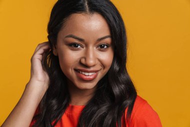 Mutlu orta yaşlı Afrikalı sıradan bir kadın sarı duvarın arkasında dikiliyor.