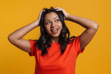 Sarı duvar arkasında dikilen orta yaşlı Afrikalı sıradan bir kadın.