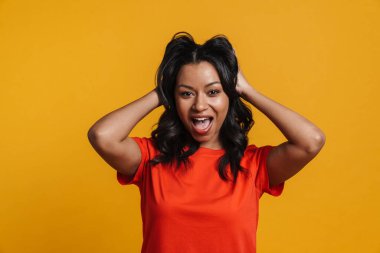 Mutlu, orta yaşlı, sıradan bir Afrikalı kadın sarı duvarın arkasında dikilip çığlık atıyor.