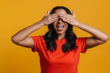 Gülümseyen ve gözlerini kapatan genç siyah mutlu kadın sarı arka planda izole edilmiş.