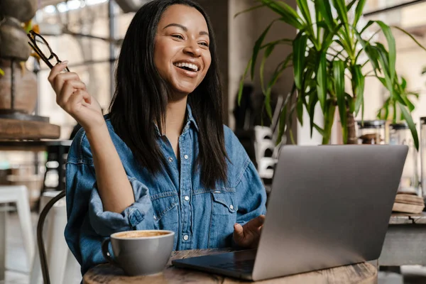 Nero Ridendo Donna Utilizzando Computer Portatile Tenendo Occhiali Mentre Seduto — Foto Stock