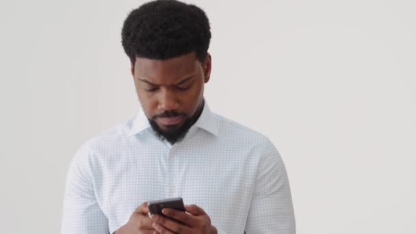 一个自信的非洲男人通过电话在白工作室里发短信 — 图库视频影像