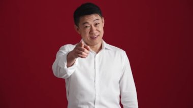 Beyaz tişörtlü pozitif Asyalı adam kırmızı stüdyodaki kameraya beni geri ara.