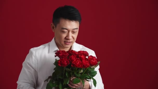 Positiv Asiatisk Man Vit Skjorta Håller Fram Bukett Röda Rosor — Stockvideo