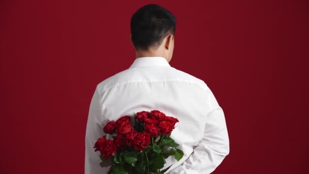 Vacker Asiatisk Man Som Håller Bukett Röda Rosor Bakom Sig — Stockvideo