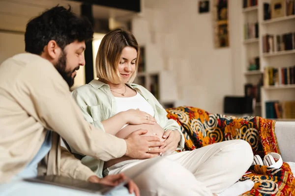 Hombre Blanco Tocando Vientre Esposa Embarazada Mientras Está Sentado Sofá — Foto de Stock