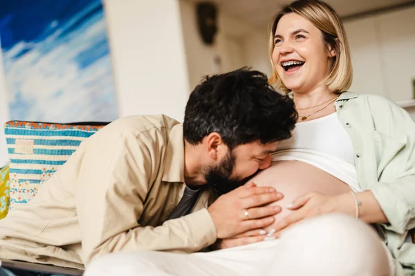 Hombre Blanco Besando Vientre Esposa Embarazada Mientras Está Sentado Sofá — Foto de Stock