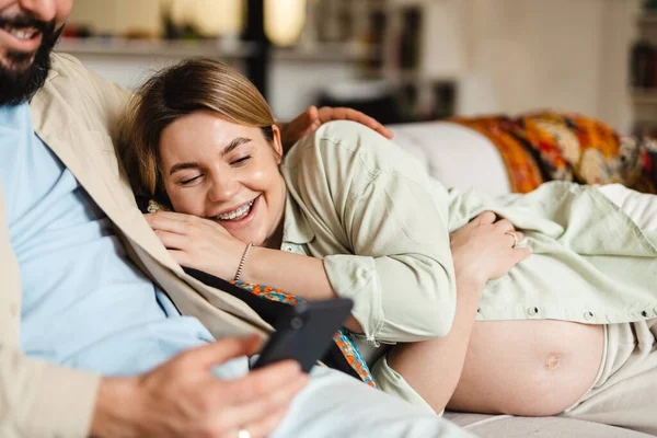 Bärtiger Mann Und Schwangere Frau Benutzen Handy Während Sie Hause — Stockfoto