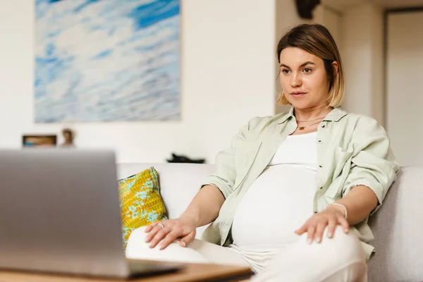 Mujer Embarazada Joven Usando Ordenador Portátil Mientras Está Sentado Sofá — Foto de Stock