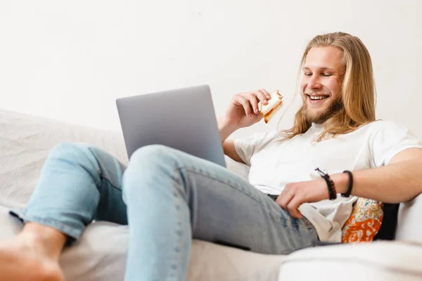 Bearded Blonde Man Eating Sandwich While Working Laptop Home — Stock Photo, Image