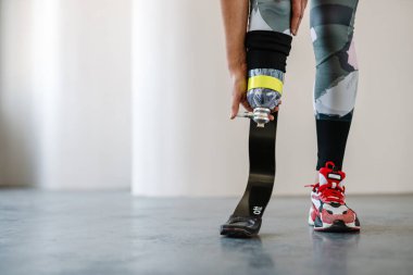 Protezli genç sporcu kadın içeride çalışırken egzersiz yapıyor.