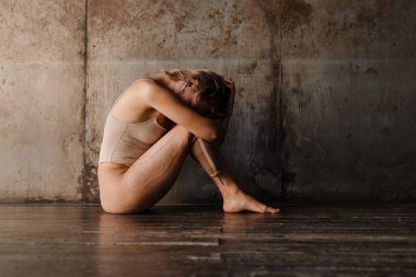 Depresyondaki genç, engelli, protez bacaklı bir kadın içeride yerde oturuyor.