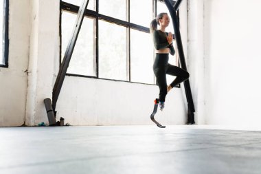 Evde yoga yaparken protez takan genç bir kadın.
