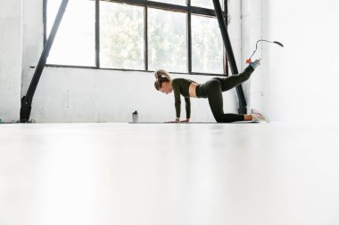 Kapalı alanda egzersiz yapan protezli genç bir kadın.