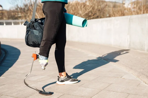 在城市街道上行走时携带假肢提包的女运动员 — 图库照片