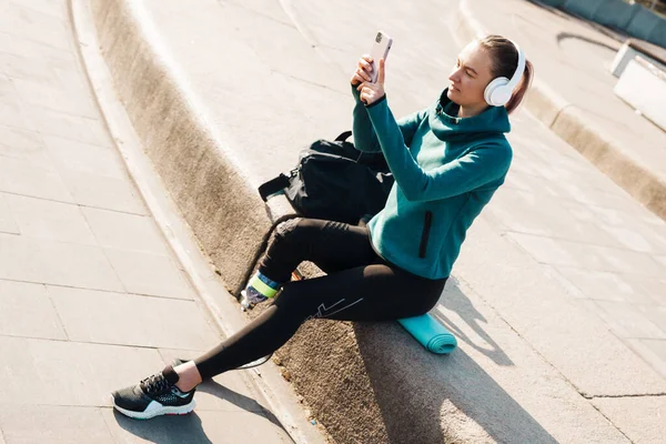 Jonge Glimlachende Sportvrouw Hoofdtelefoon Met Prothese Zittend Een Fitnessmat Met — Stockfoto