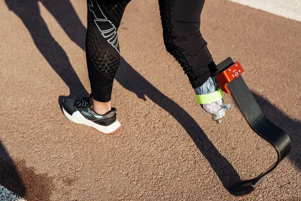 年轻的女运动员带着假肢走在城市街道上 — 图库照片