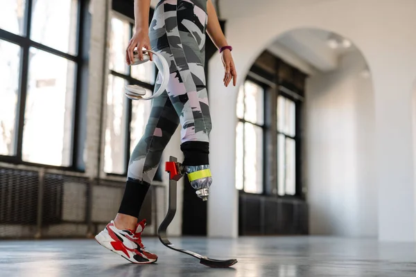 Sportskvinne Med Protese Som Holder Hodetelefoner Mens Hun Trener Innendørs – stockfoto