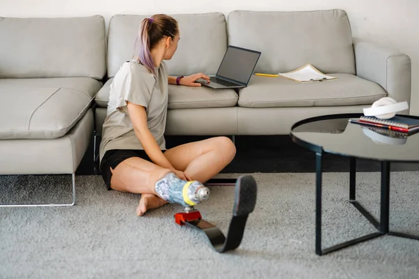Nuori Valkoinen Vammainen Nainen Jolla Proteettinen Jalka Istuu Lattialla Kannettavan — kuvapankkivalokuva