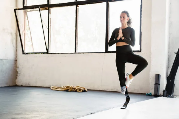 屋内ヨガの練習中に運動をする義肢のある若い女性 — ストック写真