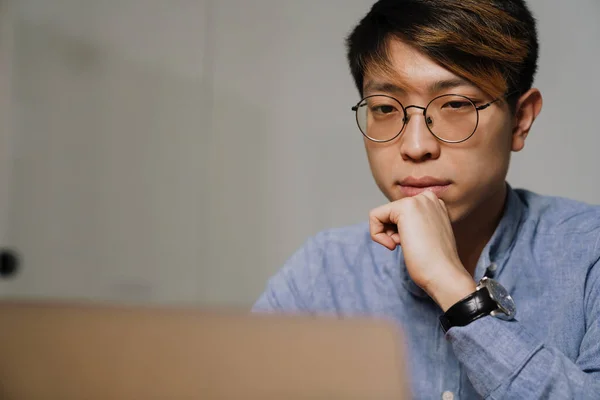 Focado Asiático Cara Óculos Trabalhando Com Laptop Enquanto Sentado Mesa — Fotografia de Stock