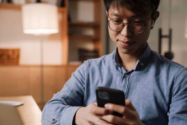 Nöjd Asiatisk Kille Hörlurar Med Mobiltelefon När Arbetar Kontoret — Stockfoto