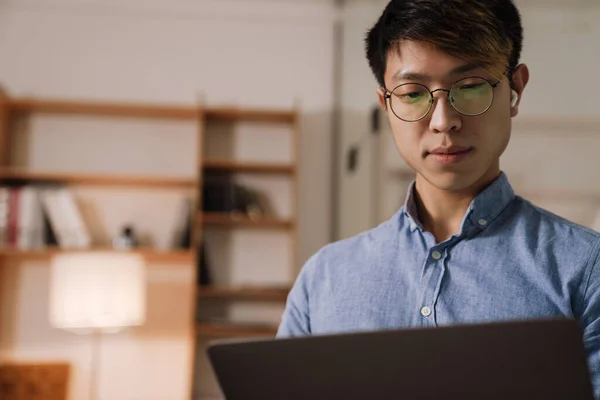 Focado Asiático Cara Fones Ouvido Trabalhando Com Laptop Enquanto Escritório — Fotografia de Stock