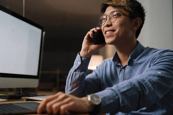 Sorridente Ragazzo Asiatico Cuffia Parlando Sul Cellulare Mentre Lavora Con — Foto Stock