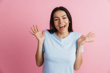 Heyecanlı İspanyol kadın pembe duvarın üzerinden izole edilmiş kameraya gülüyor.