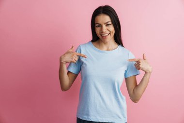 Heyecanlı İspanyol kadın gülümsüyor ve pembe duvarın üzerinde kendini işaret ediyor.