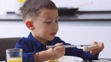 Olumlu Asyalı küçük çocuk evde pirinç kekine peynir sürüyor.