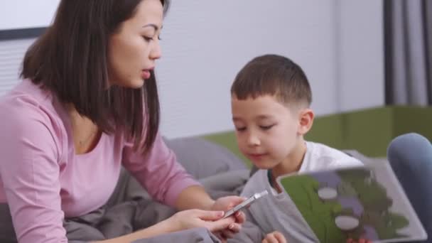 Töprengő Ázsiai Anya Fia Nézi Képeket Otthon — Stock videók