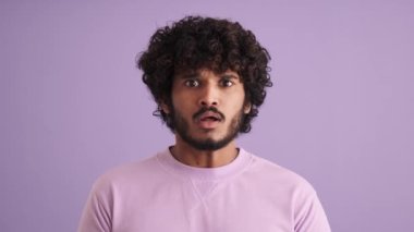 Mor stüdyoda kafasını tutan kıvırcık saçlı, korkak Hintli adam.