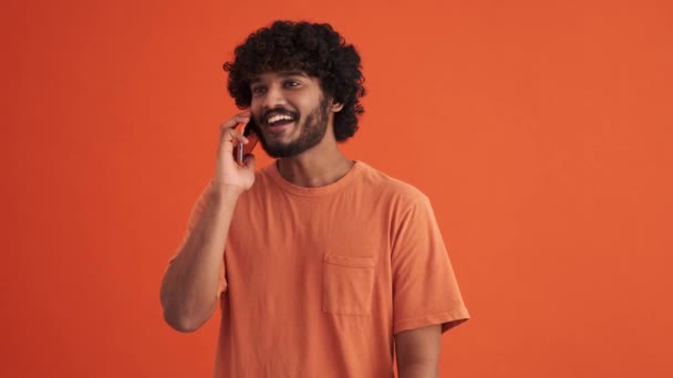 Lächelnder Gelockter Indischer Mann Telefoniert Orangefarbenen Studio — Stockvideo