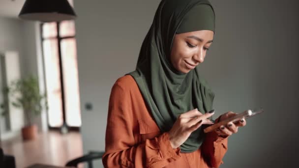 Mulher Muçulmana Feliz Digitando Por Telefone Casa — Vídeo de Stock