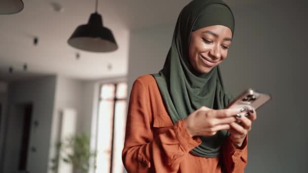 Mulher Muçulmana Sorrindo Digitando Por Telefone Casa — Vídeo de Stock