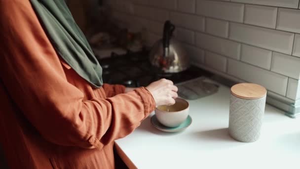 幸せなイスラム教徒の女性身に着けているヒジャーブ醸造茶でザ キッチン — ストック動画