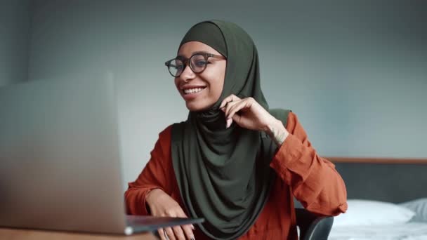 Мусульманская Улыбающаяся Женщина Очках Разговаривает Видеосвязи Домашнем Ноутбуке — стоковое видео