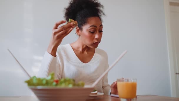 Verrast Afrikaanse Zwangere Vrouw Eten Avocado Toast Kijken Naar Telefoon — Stockvideo