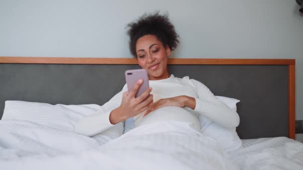 Pozitif Afrikalı Hamile Kadın Evdeki Yatakta Telefona Bakıyor — Stok video