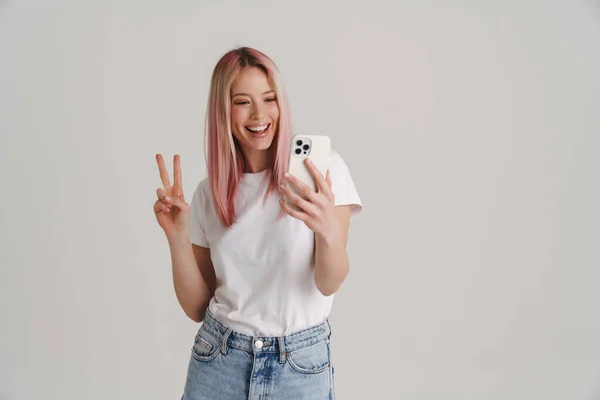 Junge Lächelnde Frau Gestikuliert Mit Friedenszeichen Während Sie Ihr Handy — Stockfoto