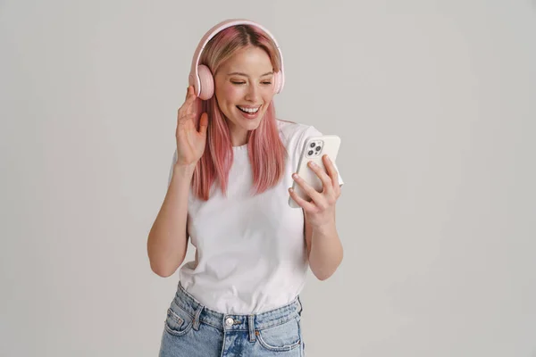 年轻的微笑的女人 带着耳机和手机听着音乐 背景是白色的 — 图库照片