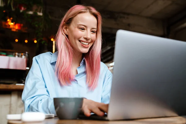 Jovem Mulher Sorridente Com Cabelo Rosa Trabalhando Com Laptop Enquanto — Fotografia de Stock